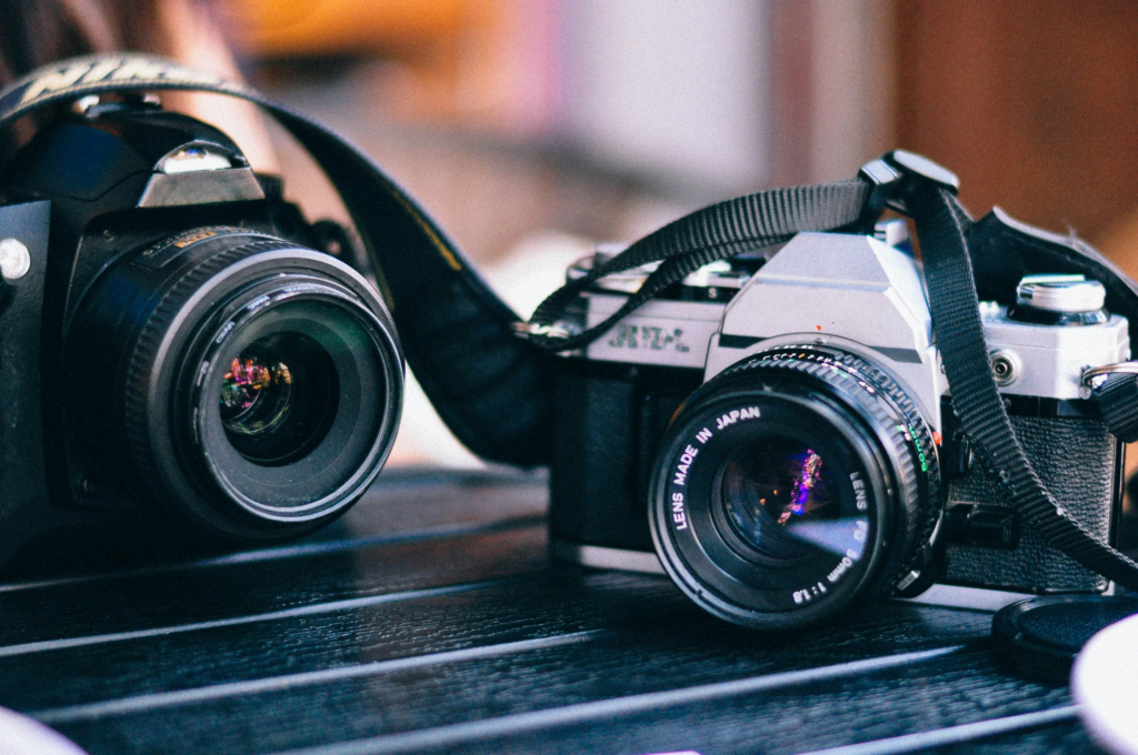 Mirrorless kamere jedna pored druge za usporedbu dizajna i veličine – logotipi uklonjeni radi neutralne prezentacije. Dvije mirrorless kamere postavljene jedna pored druge, prikazuju razlike u dizajnu i veličini, bez vidljivih oznaka brenda.